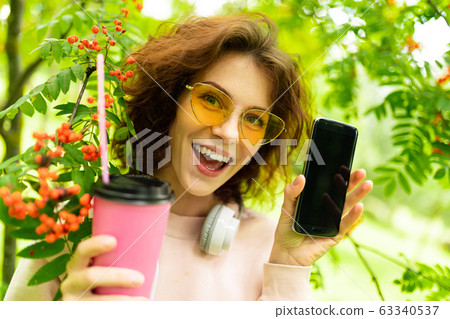 Pretty young caucasian woman go for a walk at park with coffe and earphones 63340537
