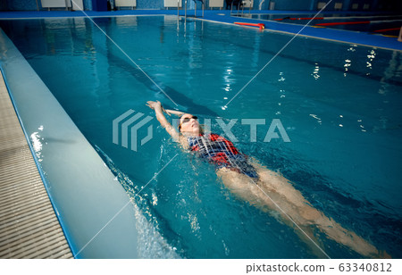 Female swimmer swimming on her back in pool Female swimmer swimming on her back in pool 63340812