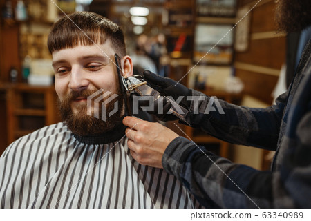 Barber with comb and clipper makes a haircut Barber with comb and clipper makes a haircut 63340989
