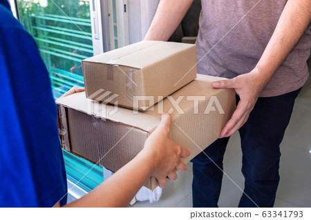 Delivery man in blue uniform handing parcel box Delivery man in blue uniform handing parcel box 63341793