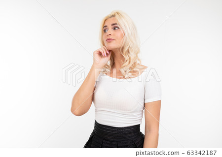 portrait of a sexy lady in a white top and black skirt posing holding her hand at the chin on a 63342187