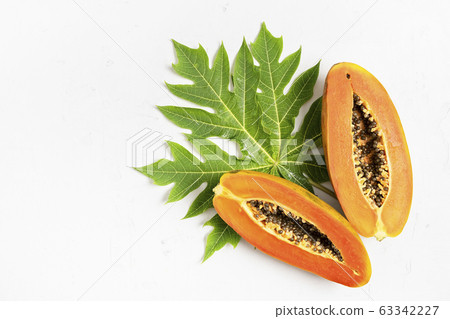 Ripe freshly cut papaya fruit with green leaf Ripe freshly cut papaya fruit with green leaf 63342227