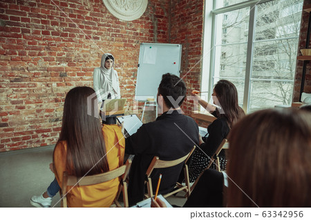 Female muslim speaker giving presentation in hall at university workshop Female muslim speaker giving presentation in hall at university workshop 63342956