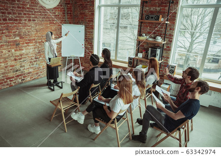 Female muslim speaker giving presentation in hall at university workshop 63342974