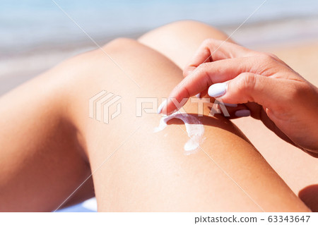 Closeup on female hand applying sunblock on her Closeup on female hand applying sunblock on her 63343647