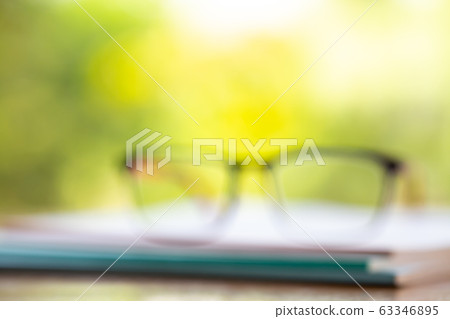 Blurred black eyeglasses with three white notebooks on wooden table, Bokeh garden background, Close up & Macro shot, Stationery concept 63346895