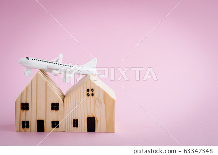 White airplane and wooden house model on pink background White airplane and wooden house model on pink background 63347348