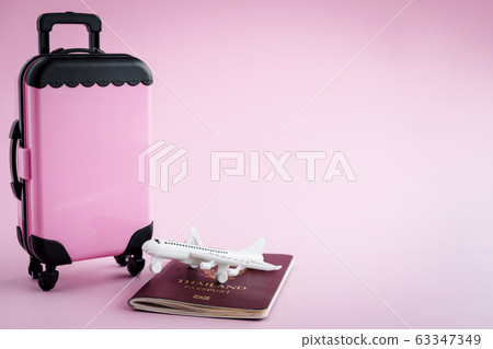 Pinky luggage with Thai passport and white airplane model on pink background 63347349