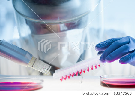 Scientist working in the corona virus vaccine development laboratory research with a highest degree of protection gear. Scientist working in the corona virus vaccine development laboratory research with a highest degree of protection gear. 63347566