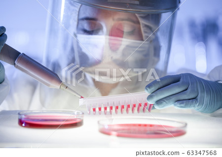 Female scientist working in the corona virus vaccine development laboratory research with a highest degree of protection gear. Female scientist working in the corona virus vaccine development laboratory research with a highest degree of protection gear. 63347568