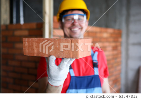 Smiling male builder showing fine quality brick material in camera Smiling male builder showing fine quality brick material in camera 63347812