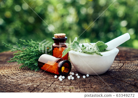 Bottle of homeopathic granules and medicinal herbs 63349272