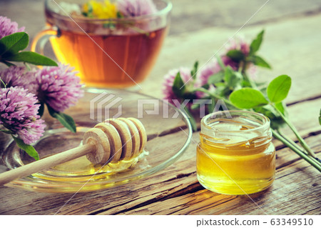 Clover flowers, herbal tea cup, honey jar on table 63349510