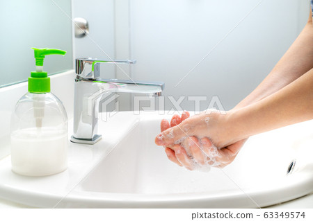 Woman washing her hands with soap at the sink Woman washing her hands with soap at the sink 63349574