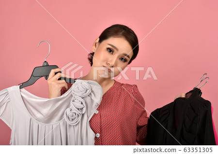 Asian woman choosing cloth in studio shot, What to wear selection for proper dressing Asian woman choosing cloth in studio shot, What to wear selection for proper dressing 63351305