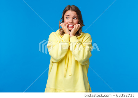 Scared timid, insecure european female feeling panic and afraid staying alone at home, biting fingernails look away as trembling fear, standing unsafe place over blue background Scared timid, insecure european female feeling panic and afraid staying alone at home, biting fingernails look away as trembling fear, standing unsafe place over blue background 63352735