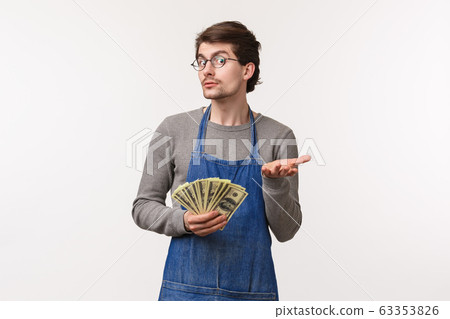 Small business, finance and career concept. Portrait of greedy caucasian male in apron pointing with hand at camera and holding cash, acting clueless dont know anything, dont tell how he got rich 63353826