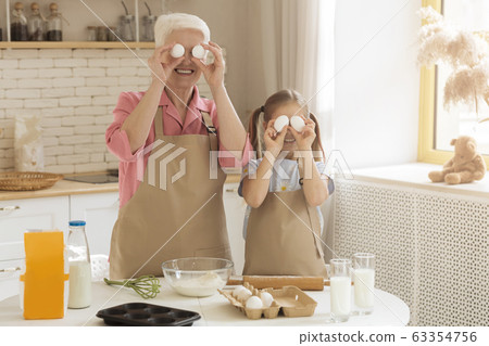 Granny and granddaughter playing while cooking at home, blank space 63354756