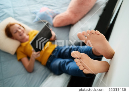 Little Redhead Girl Watching Cartoons At Home With Tablet Little Redhead Girl Watching Cartoons At Home With Tablet 63355486