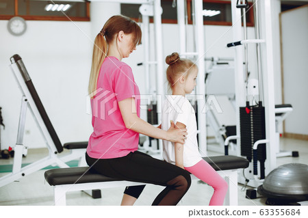 Mother with little daughter are engaged in gymnastics in the gym 63355684