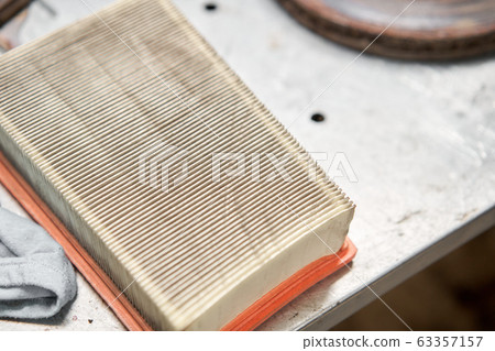 Old dirty automotive engine air filter on metal table of an auto mechanic. Auto repair concept. 63357157