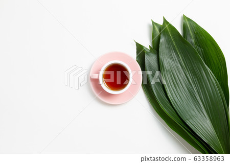 Cup of black tea with fresh green leaves on white background. Flat lay, top view, copy space 63358963