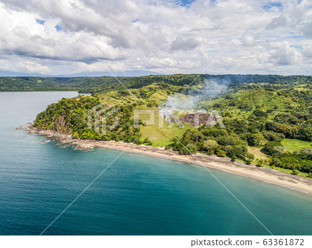 Aerial shot of small fire at the tropical coastline by Playa Arenillas in Costa Rica peninsula Papagayo coast guanacaste 63361872