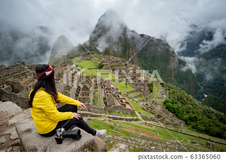 Young Asian woman traveler looking at Machu Picchu Young Asian woman traveler looking at Machu Picchu 63365060