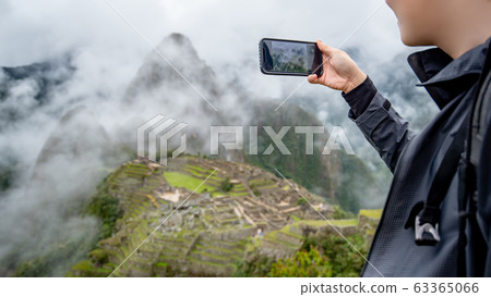 Asian man tourist taking photo of Machu Picchu Asian man tourist taking photo of Machu Picchu 63365066