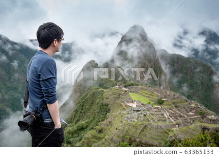 Young Asian man traveler looking at Machu Picchu Young Asian man traveler looking at Machu Picchu 63365133