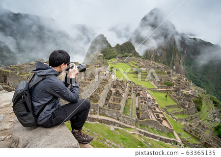 Asian man traveler taking photo at Machu Picchu 63365135