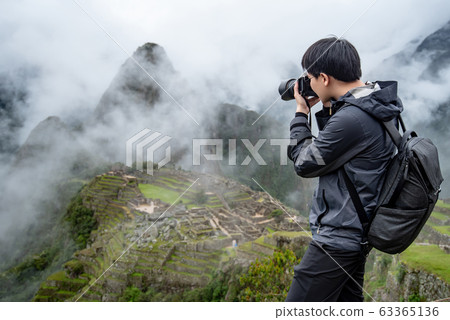 Asian man traveler taking photo at Machu Picchu 63365136