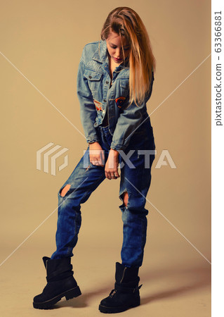 teenage girl in jeans stands looking down 63366881