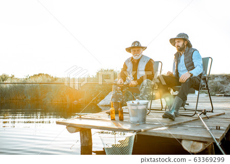 Grandfather with adult son fishing on the lake Grandfather with adult son fishing on the lake 63369299