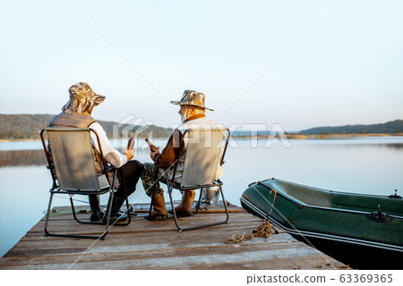 Grandfather with adult son fishing on the lake Grandfather with adult son fishing on the lake 63369365