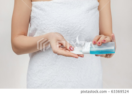 close-up woman in towel holding cotton pad and makeup remover 63369524