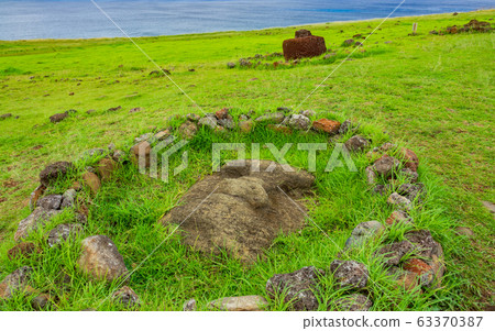 Moai buried on the ground surrounded with stones Moai buried on the ground surrounded with stones 63370387