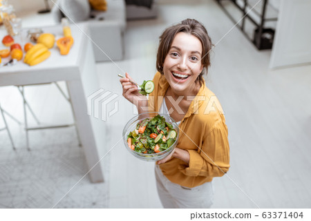 Woman eating salad at home 63371404
