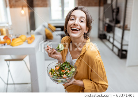 Woman eating salad at home Woman eating salad at home 63371405
