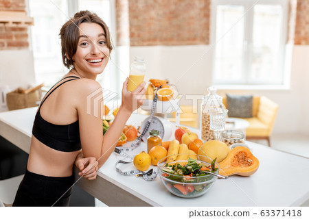 Sports woman with healthy food on the kitchen Sports woman with healthy food on the kitchen 63371418