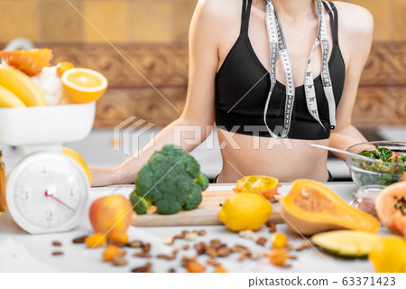 Sports woman with healthy food on the kitchen Sports woman with healthy food on the kitchen 63371423