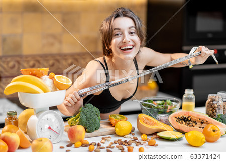 Sports woman with healthy food on the kitchen Sports woman with healthy food on the kitchen 63371424