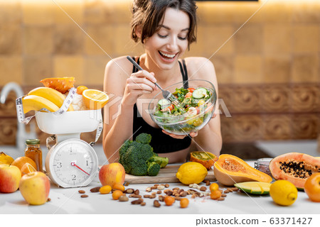 Sports woman with healthy food on the kitchen Sports woman with healthy food on the kitchen 63371427