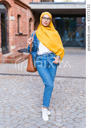 Beautiful Arabic muslim woman wearing yellow hijab, stylish female portrait over city street. Beautiful Arabic muslim woman wearing yellow hijab, stylish female portrait over city street. 63373152