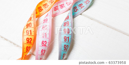 Close up of colorful measure tapes on wooden Close up of colorful measure tapes on wooden 63373958