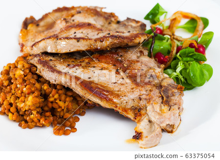 Cooked fried pork meat chop with lentils, herbs and berries garnish Cooked fried pork meat chop with lentils, herbs and berries garnish 63375054
