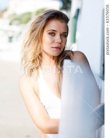 Young female in swimsuit posing near hotel fence at sea shore Young female in swimsuit posing near hotel fence at sea shore 63376056