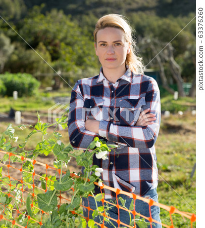 Female gardener standing in homestead Female gardener standing in homestead 63376260