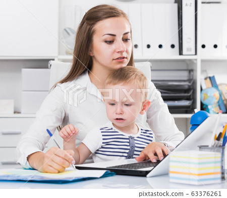 Mom with child is working behind laptop 63376261
