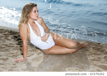 Young sexy girl in swimsuit and hat relaxation at sandy beach Young sexy girl in swimsuit and hat relaxation at sandy beach 63376262